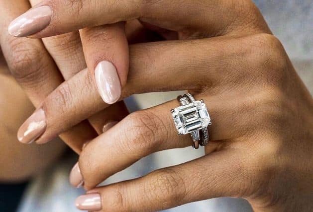 Hands wearing 3ct Emerald cut diamond ring