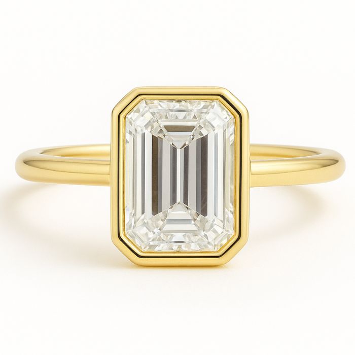 Bezel set diamond engagement ring with a emerald cut diamond in yellow gold